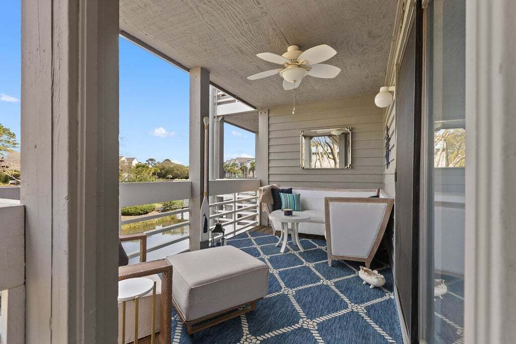 A covered outdoor area with a ceiling fan, a small table, a sofa, and a patterned floor.