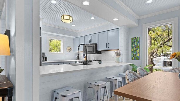 A modern kitchen with a white island, bar stools, and a dining table. - Cozy 3BR / 3.5 BA Retreat - Neighborhood Pool!  access included! (Johns Island)