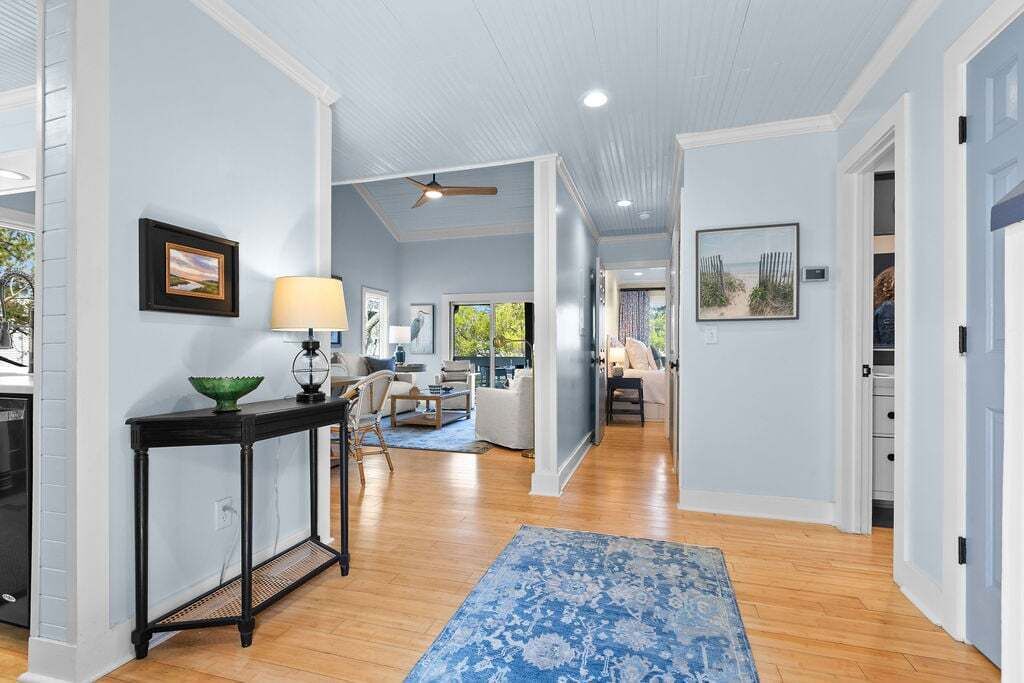 Un couloir doté d’un plancher en bois, d’un tapis à motifs bleus et d’un ventilateur de plafond.