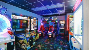Quarto com jogos de fliperama, incluindo 'Big Buckin' e 'Bike Race', e um chão com padrão de estrelas.