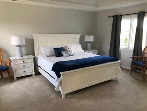 A bedroom with a large bed, two bedside tables, a chair, and a window with curtains. - Spectacular Marsh Views! Walk to North Beach!  Sleeps 8! Amenity Access included! (Seabrook Island)