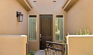 A beige exterior wall with a dark brown door, two windows with green curtains, and a small outdoor area with plants. - Above Par GOLF COURSE VIEWS!! 2 Community Pools! (Washington)