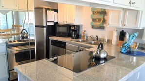 Una cocina moderna con electrodomésticos de acero inoxidable, encimeras de granito y lavavajillas integrado.