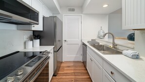 A modern kitchen with white cabinetry, a stainless steel refrigerator, a built-in oven, and a sink with a faucet. - View of Edisto & Ocean! Walk to Pools, Golf! Amenity Access included! (Seabrook Island)