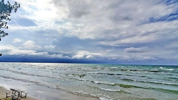 Une plage avec une table de pique-nique et des vagues de l’océan.