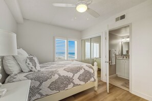 A bedroom with a bed, a ceiling fan, and a bathroom visible through an open door.