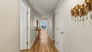 Un pasillo con puertas blancas, suelo de madera y una placa numérica en la pared.