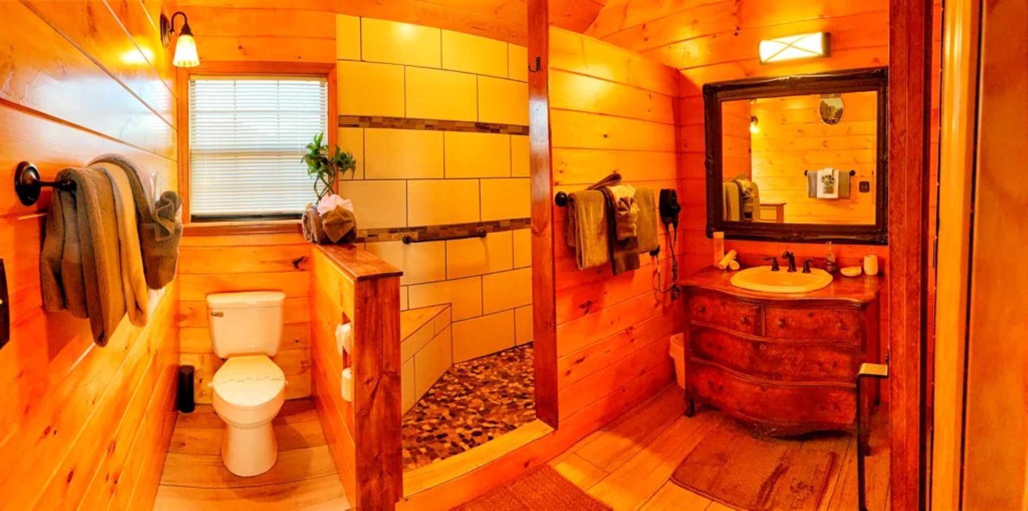 Une salle de bain rustique, aménagée dans une cabane en bois, avec des toilettes, un lavabo et un miroir.