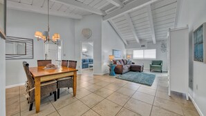 A spacious living area with a dining table, a sofa set, and a green armchair. - Beach Service Included, Private Beach, Chateau La Mer 10E! (Destin)