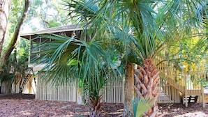 A house with a wooden deck, surrounded by palm trees and a wooden fence. - Adorable Cottage! Pet Friendly! 3 BR/2 BA w/ Golf Views! Amenity access! (Seabrook Island)