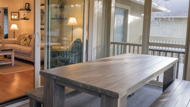 A wooden dining table with benches in a well-lit room with a glass door leading to a balcony. - Adorable Cottage! Pet Friendly! 3 BR/2 BA w/ Golf Views! Amenity access! (Seabrook Island)