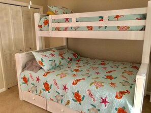 Una cama litera con una cama inferior y una cama individual, ambas con cubrecama estampado floral.