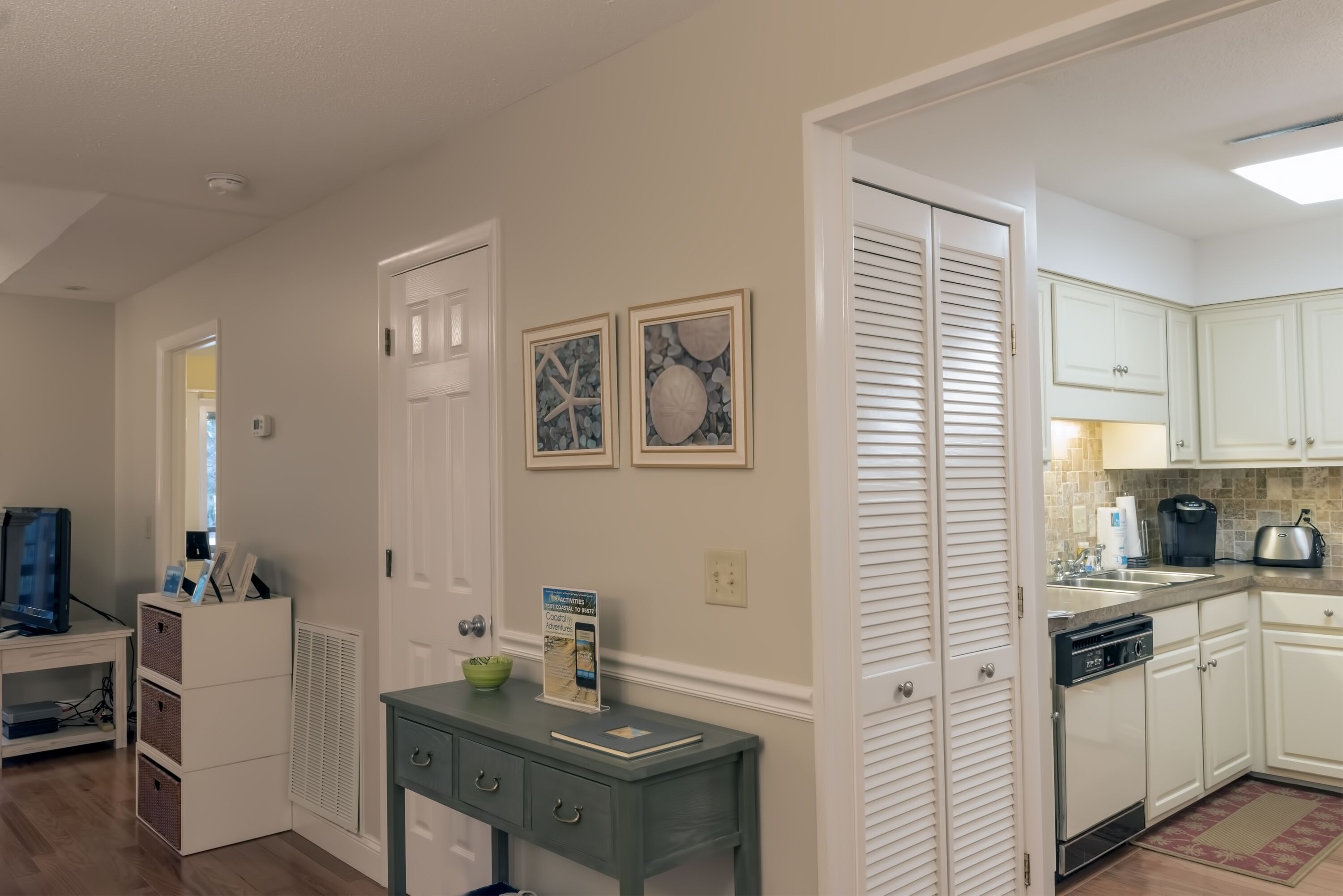 A modern kitchen with white cabinets, a built-in dishwasher, and a countertop with a coffee maker.