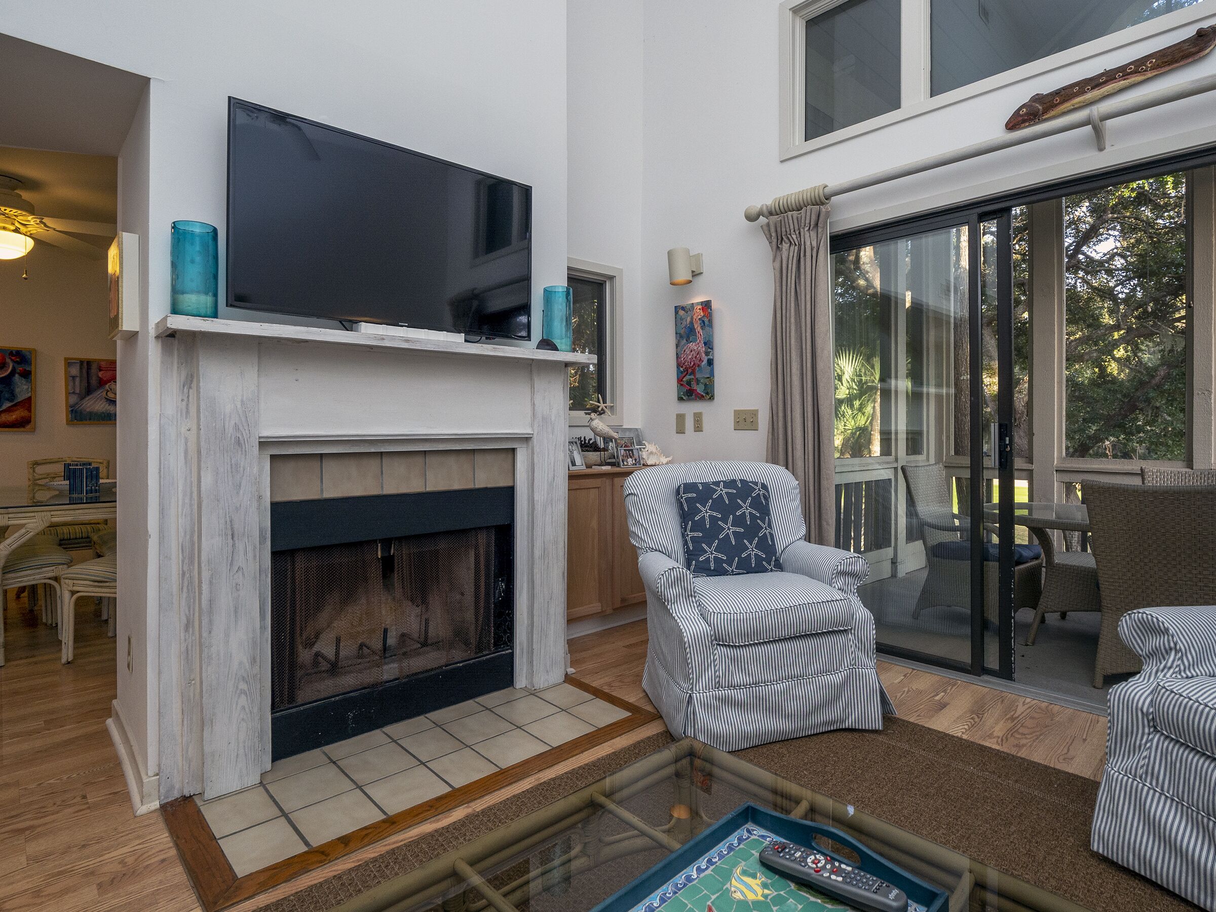 A living room with a fireplace, a television, and a dining area with a glass door leading outside.