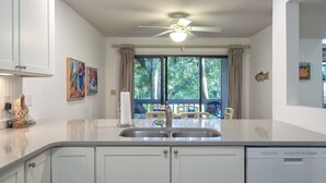 Una cocina moderna con armarios blancos, un lavamanos doble y un ventilador de techo.