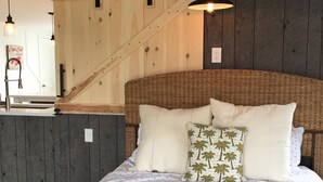 A bed with a woven headboard, white bedding, and two pillows, one with palm tree patterns. - "Sea Gypsy"  Waterfront newly renovated, beautiful views, dock, beach! (Dennis)