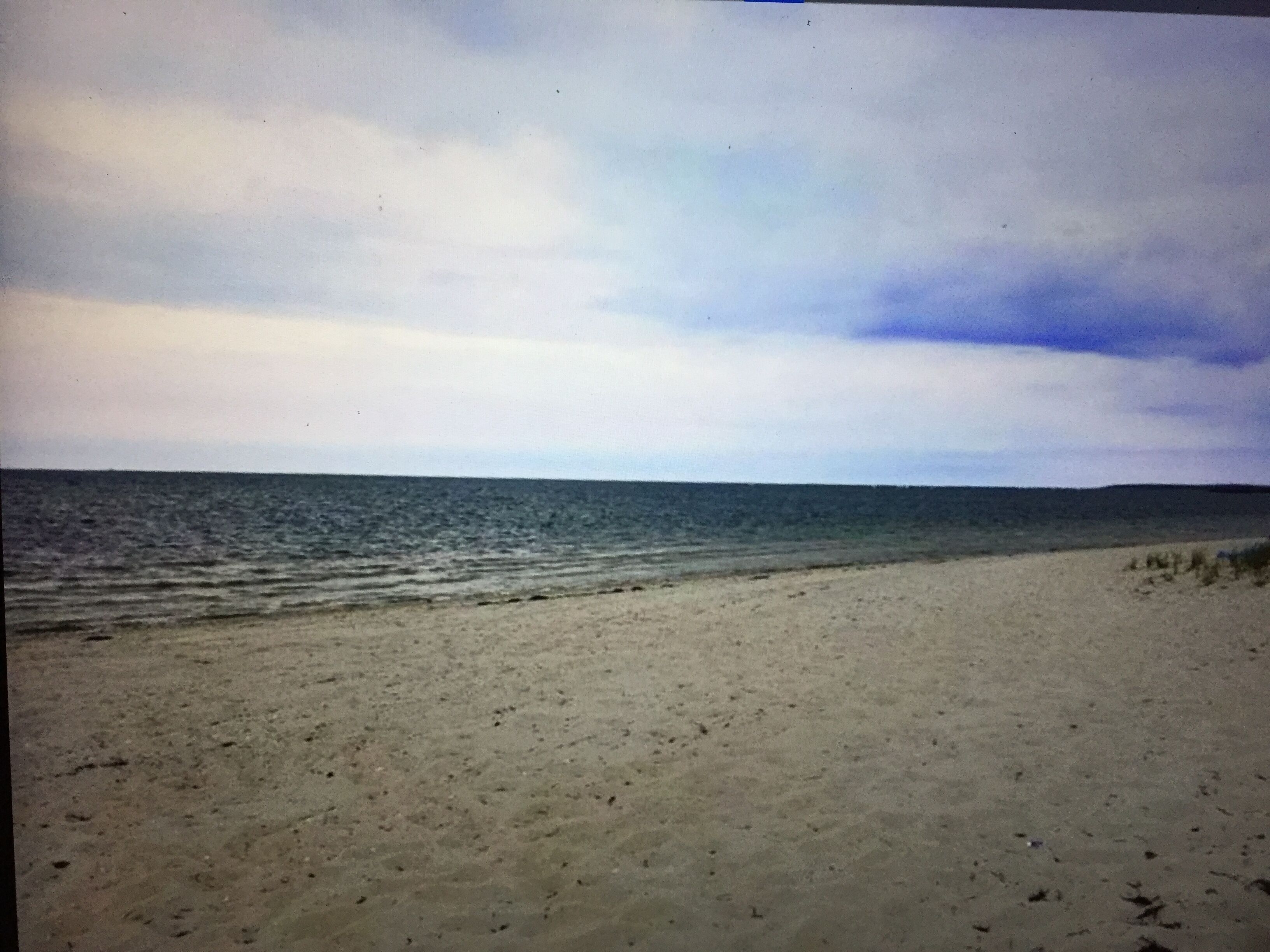 Een strand met een zandstrand en een rustige zee onder een bewolkte lucht.