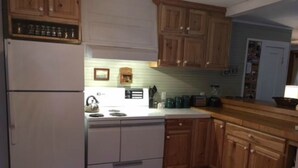 Una cucina compatta con mobili in legno, un frigorifero bianco e un piano cottura.