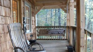 Un portico in legno con una poltrona a dondolo e una panchina.