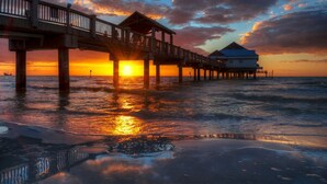 Un muelle que se adentra en el océano con una casa al final.