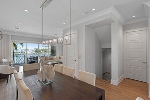 A spacious dining area with a wooden table, white chairs, and a decorative sculpture.