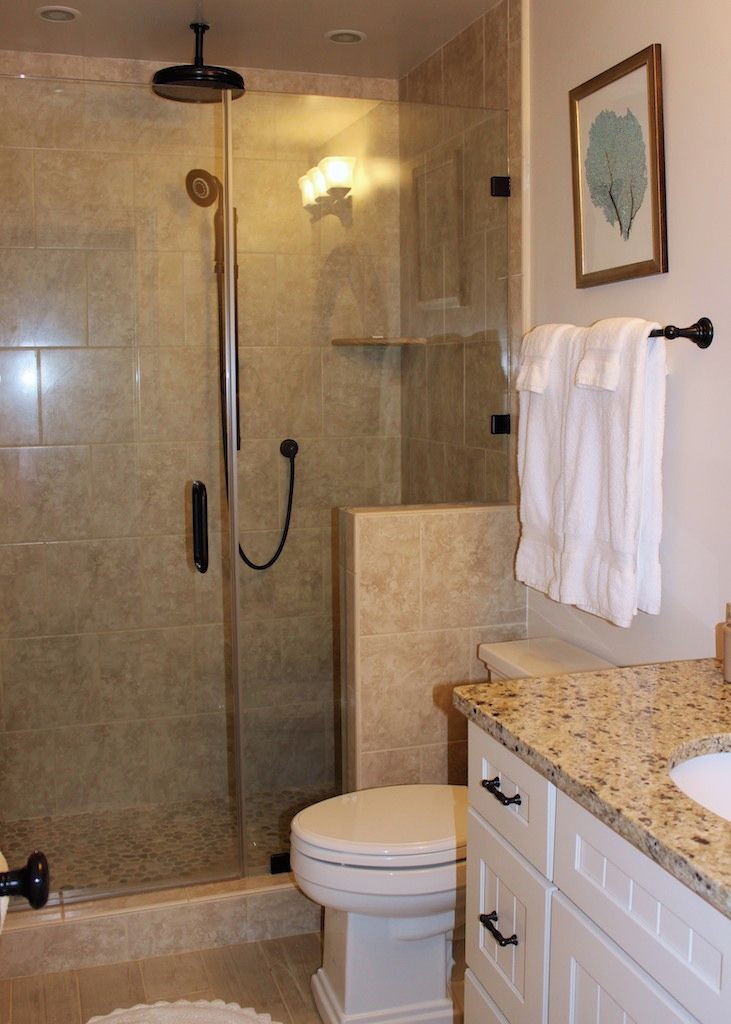A bathroom with a glass-enclosed shower, a toilet, and a vanity with a granite countertop.