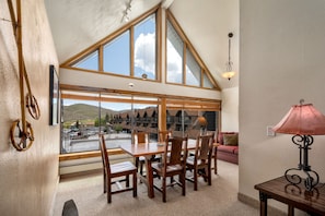 Enjoy a mountain view from the large windows in this room, featuring a dining table and comfortable seating.
