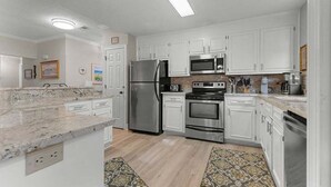 A modern kitchen with white cabinets, stainless steel appliances, and a granite countertop.