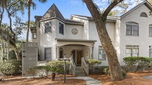 A two-story house with a front porch, a staircase, and a gated entrance.