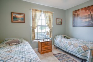 Un dormitorio con dos camas, una mesita de noche, una ventana con cortinas y decoración en la pared.