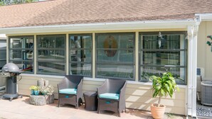 A covered patio with wicker chairs and a potted plant. - Charming home looks out onto Hidden Lakes Golf Course. 1152F (New Smyrna Beach)