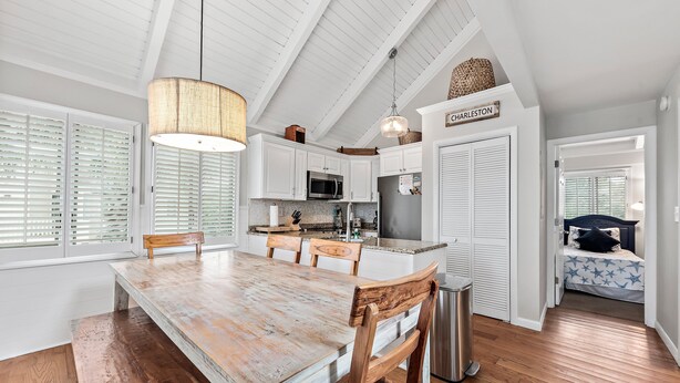 Una cocina amplia con una gran mesa de madera, armarios blancos y una lámpara colgante.