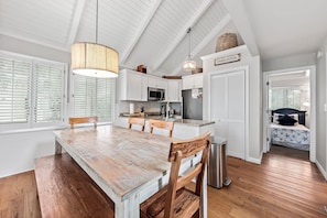 Une cuisine spacieuse avec une grande table en bois, des meubles blancs et un luminaire suspendu.