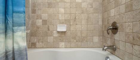 A bathroom with a bathtub, a shower curtain, and tiled walls.