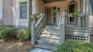 A wooden staircase leading to a porch with a covered entrance and flower boxes.