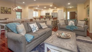 A spacious living room with two grey sofas, a coffee table, and a ceiling fan.