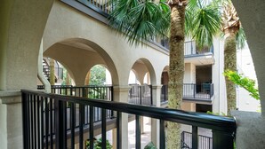 Ein mehrgeschossiges Atrium mit einem zentralen, offenen Innenhof, umgeben von Bögen und Palmen.
