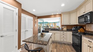 A kitchen with white cabinets, a granite countertop, a black stove, and a microwave. - Ocean View 3BR Spinnaker! Steps to Beach, Pools, Dining, Golf! Amenity access included! (Seabrook Island)