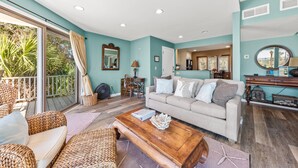 A spacious living room with a large sofa, a coffee table, wicker furniture, and a view of the outdoors. - Ocean View 3BR Spinnaker! Steps to Beach, Pools, Dining, Golf! Amenity access included! (Seabrook Island)