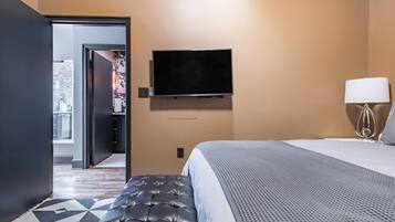 Une chambre d’hôtel avec un lit, un téléviseur fixé au mur, une lampe et un tapis à motifs.
