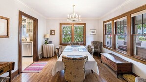 A dining room with a wooden table, chairs, a chandelier, and large windows with a view. - 4 Beds, 4 bathrooms! 1 block to town shops, bars, bowling, canoeing, and parks! (Flushing)
