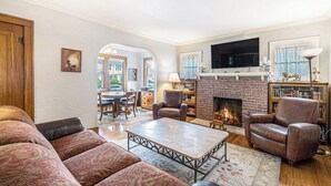 A living room with a fireplace, leather armchairs, a coffee table, and a television. - 4 Beds, 4 bathrooms! 1 block to town shops, bars, bowling, canoeing, and parks! (Flushing)