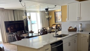 Una cocina moderna con una isla central, muebles blancos y un lavavajillas integrado.