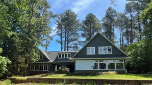 A two-story house with a dark green exterior, large windows, and a covered porch.