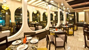 Restaurant amb diverses taules i seients, amb una decoració moderna, finestres d'arc i lluminàries penjants.