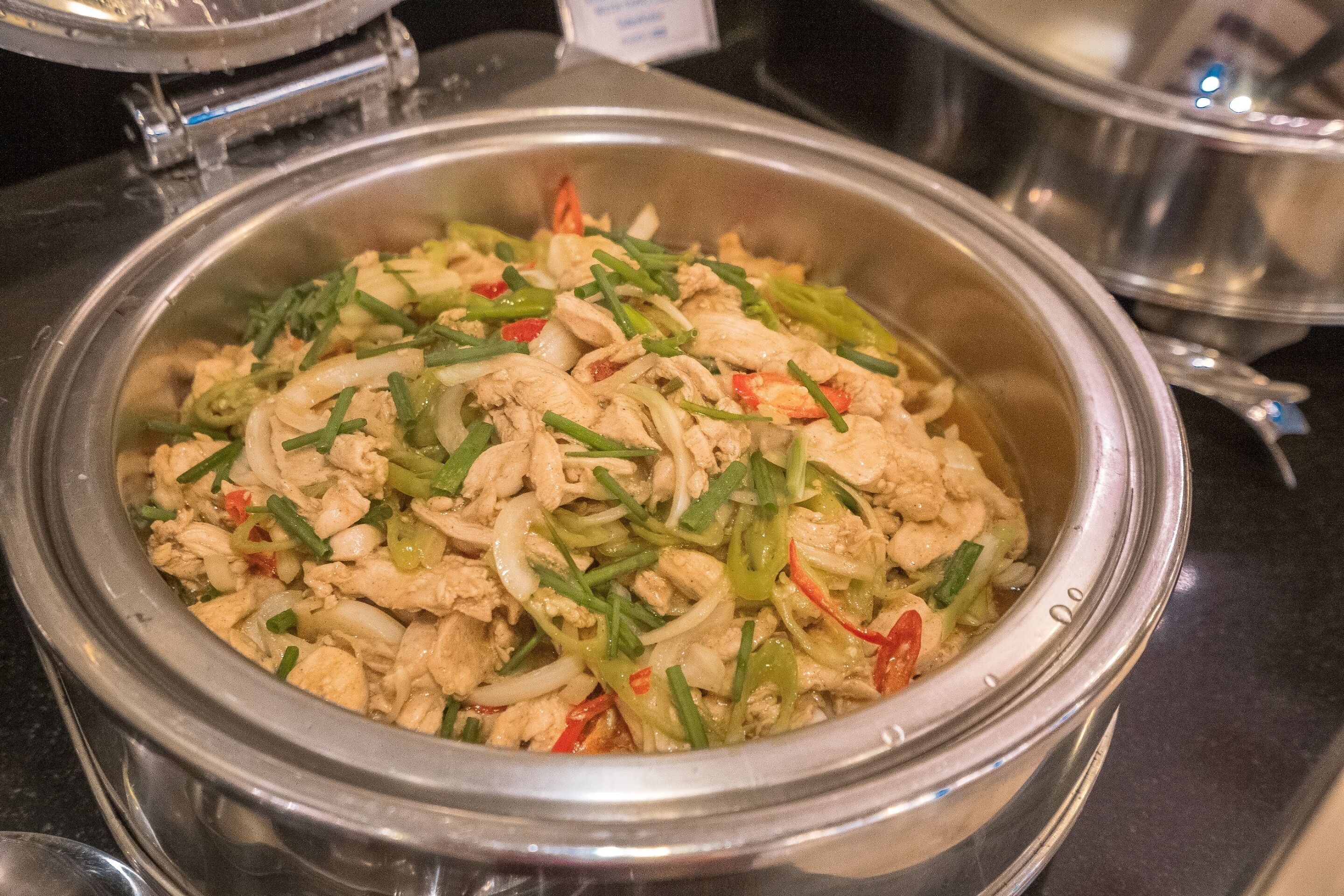 A buffet with a variety of dishes including stir-fried chicken and vegetables.