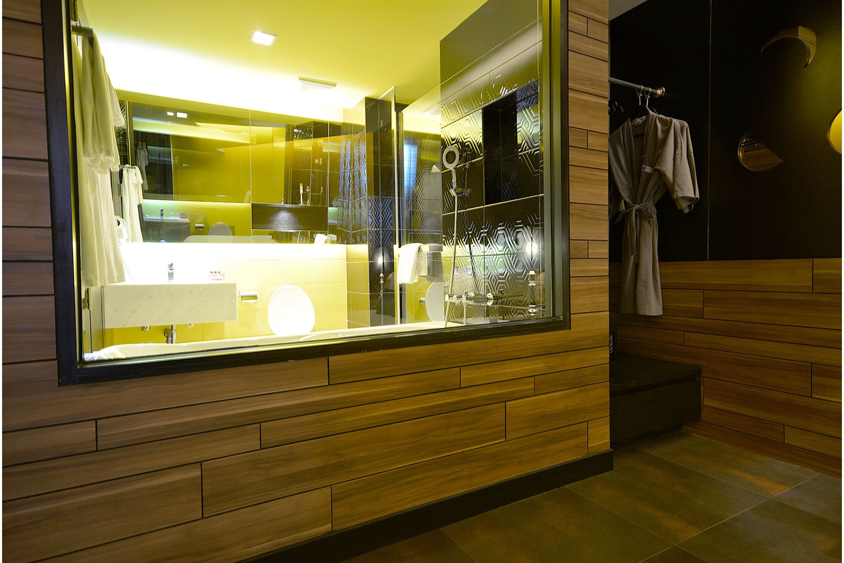 A modern bathroom with a large mirror, wooden paneling, and a towel rack.
