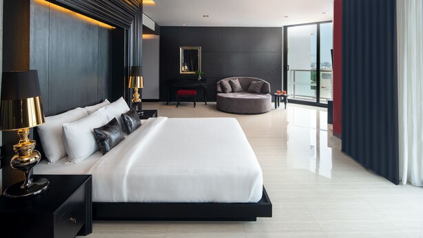 Habitació d'hotel moderna amb un llit gran, zona d'estar i vistes a la ciutat.