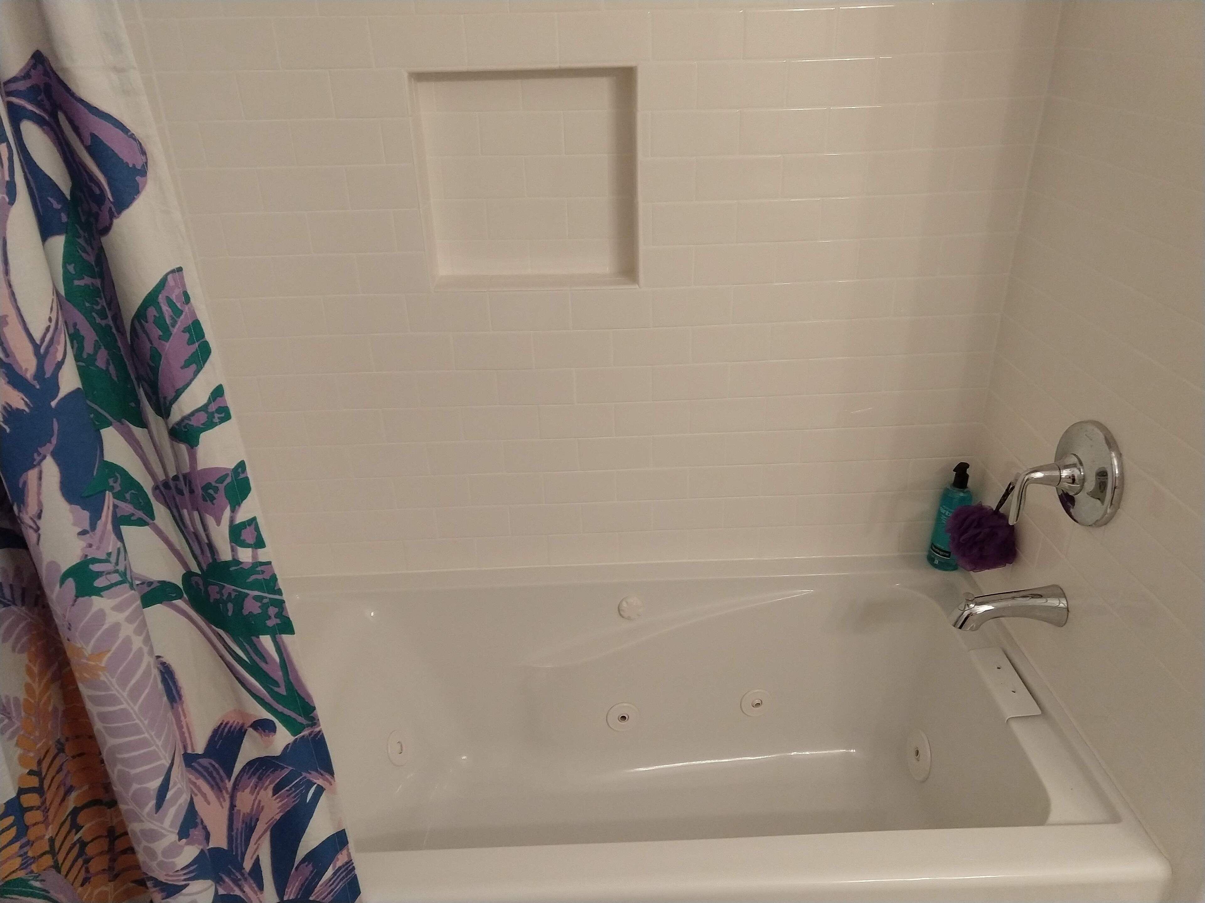 A bathroom with a bathtub, a showerhead, and a towel rack.