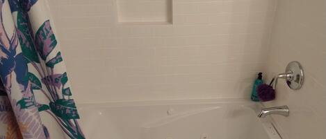A bathroom with a bathtub, a showerhead, and a towel rack.